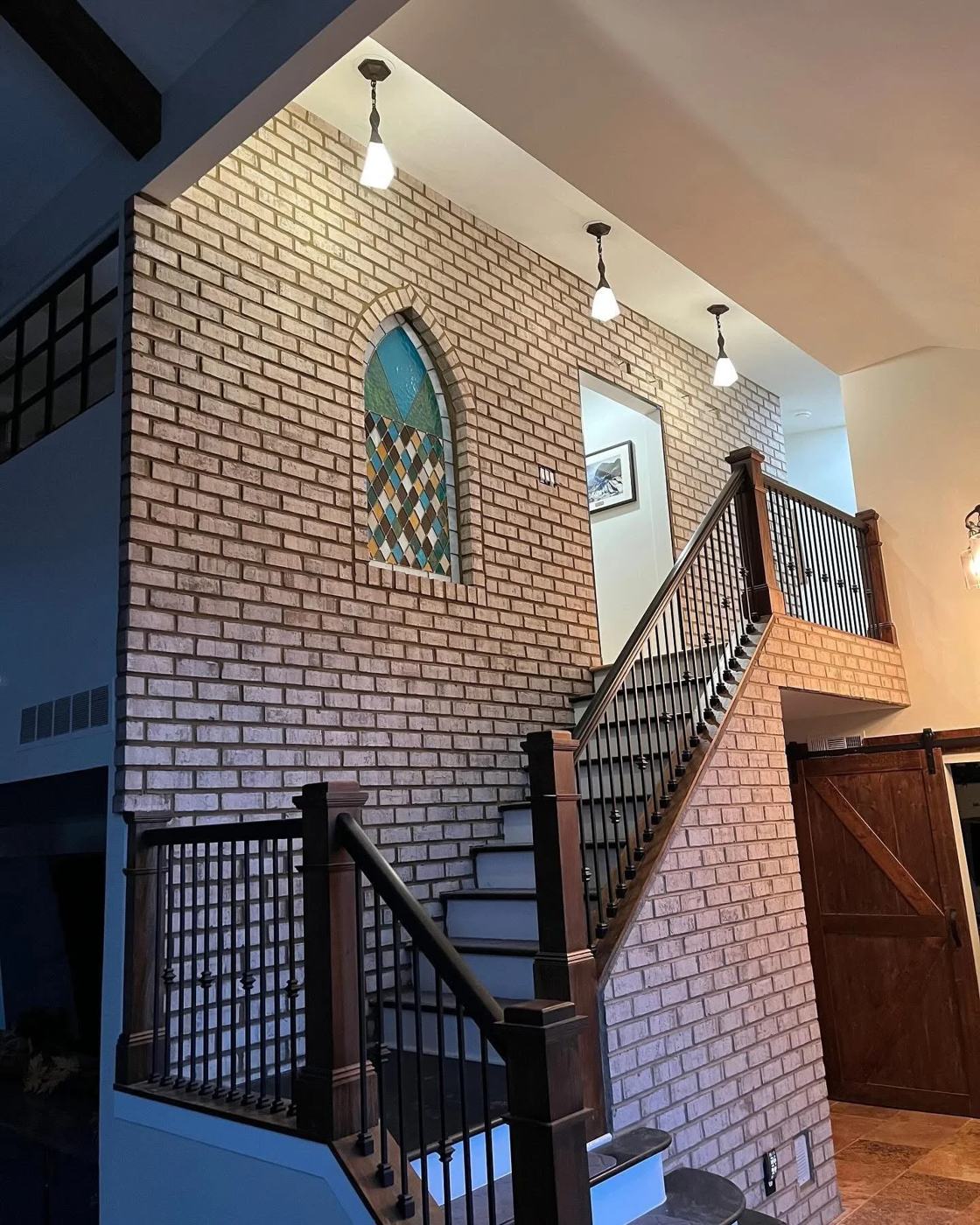 Brick accent wall rising through an open stairwell
