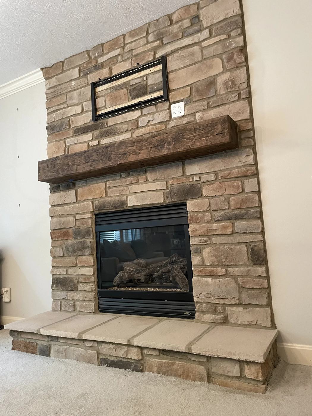 Stacked stone fireplace with a rustic beam mantel