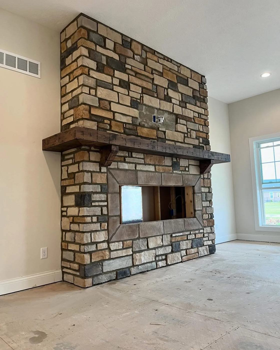 Wide stone fireplace with a heavy timber mantel