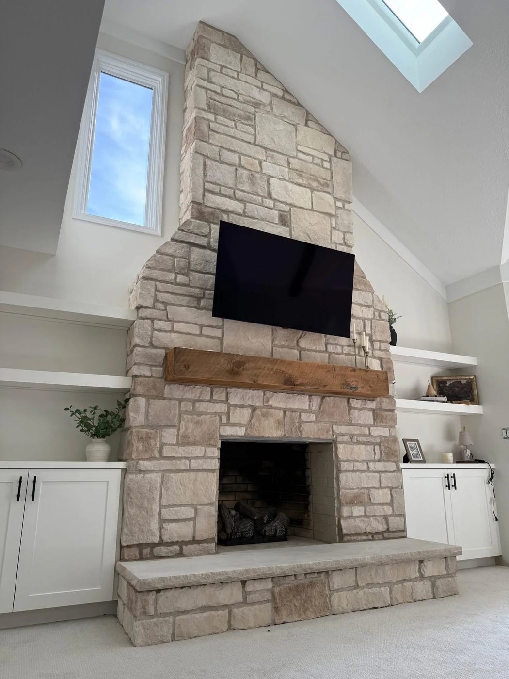 Stone fireplace and built ins beneath a skylight